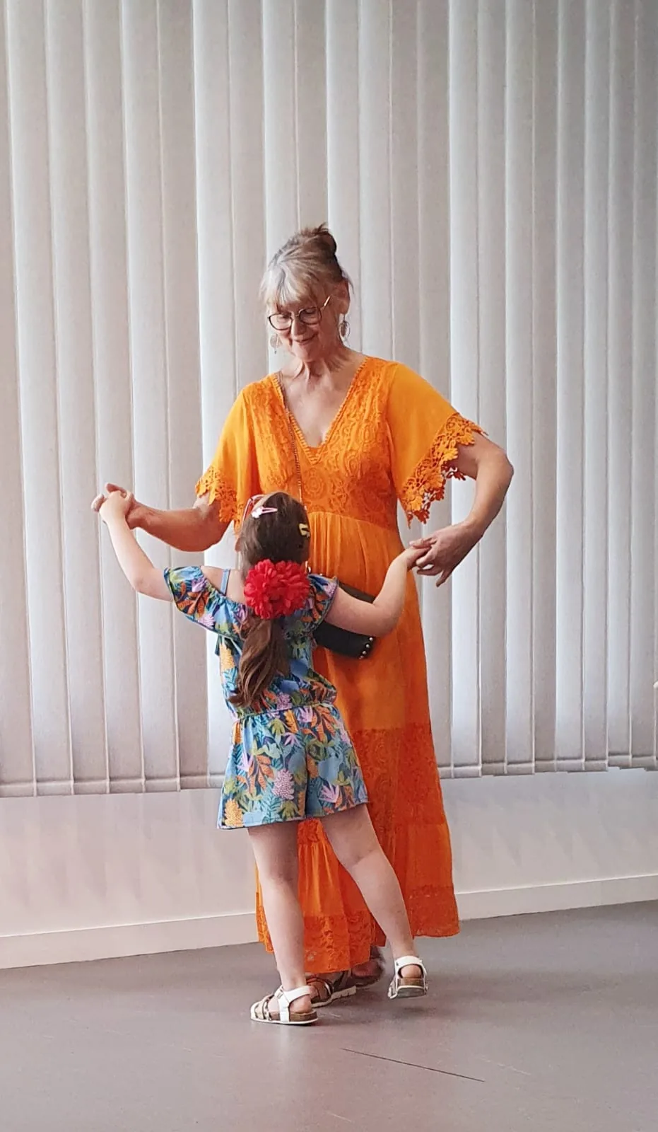 Une musicienne en robe orange danse avec une enfant.