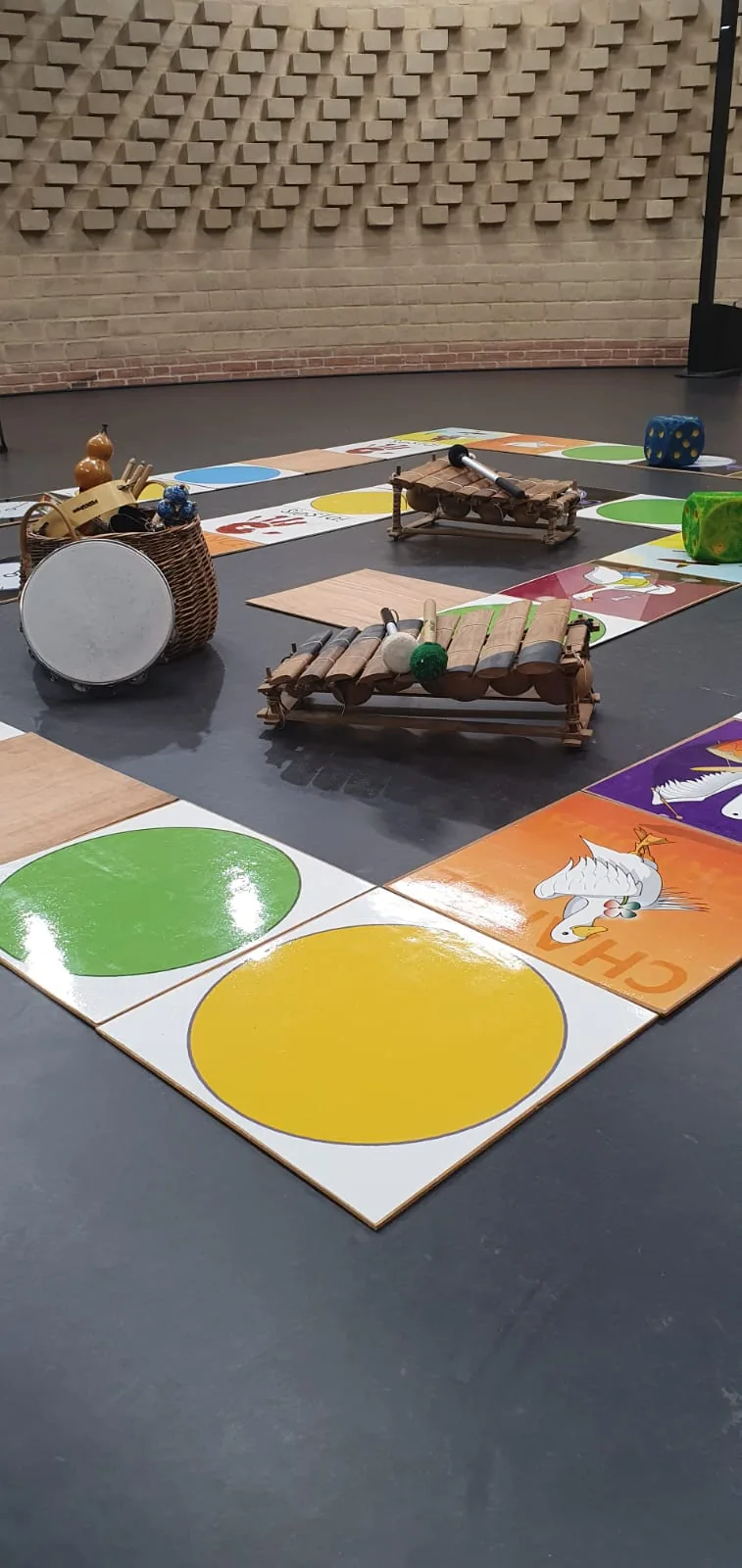 Le plateau géant avec ses cases colorées et des instruments posés au sol.